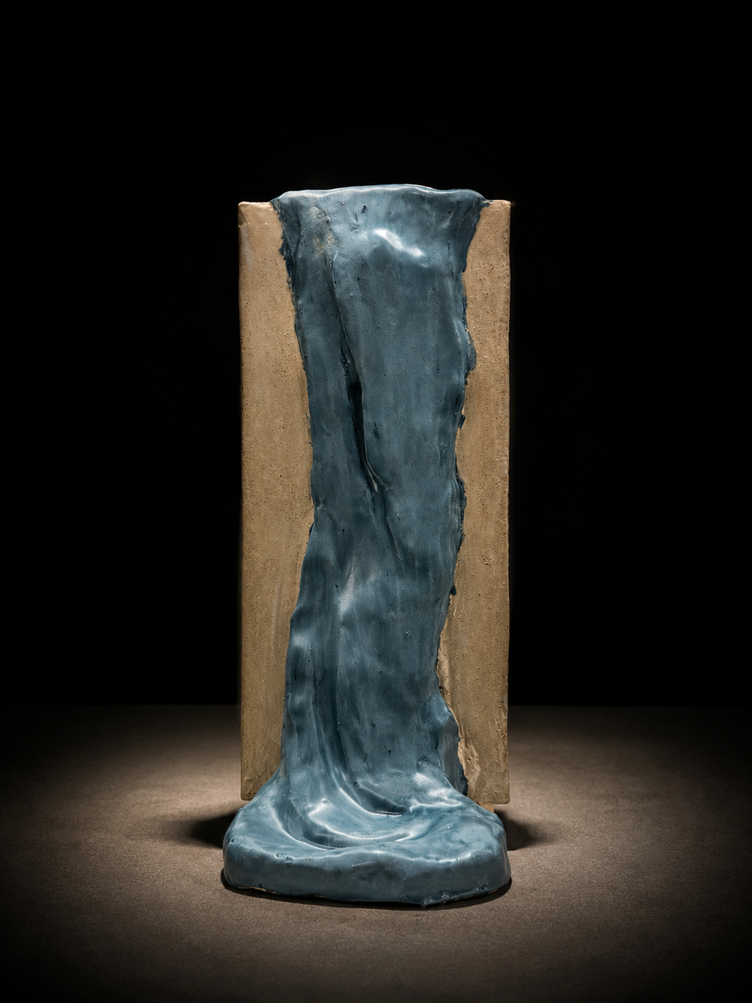 Vessel with three rigid sand-toned sides and one overflowing glazed side